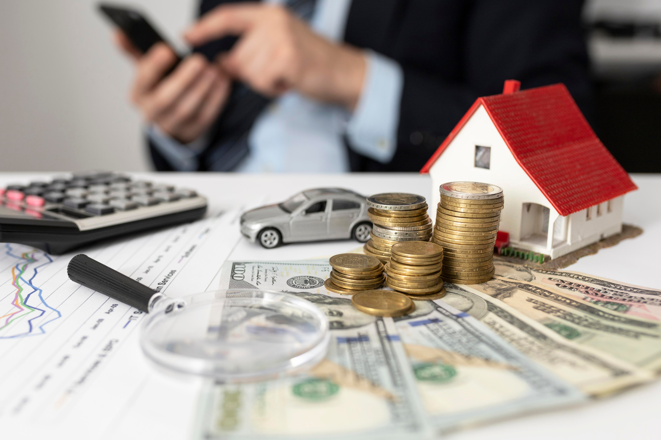Inversor analizando opciones de flipping inmobiliario con una calculadora, dinero en efectivo y una maqueta de casa en la mesa.