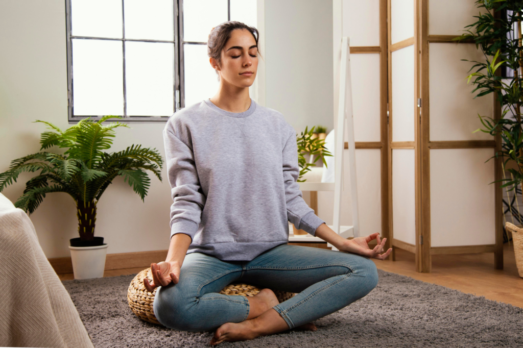 Mujer meditando en casa en un espacio tranquilo y armonioso, promoviendo el equilibrio y bienestar desde el hogar.
