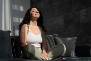 Mujer meditando en su sala, disfrutando de un momento de autoconexión y tranquilidad interior.