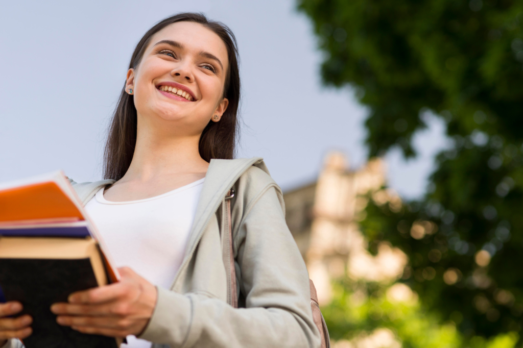 Estudiante sonriente cargando libros en Mérida, representando el estilo de vida universitario cerca de los departamentos Hatha.
